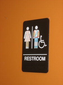 Sign for the bathroom at Bloomington Bagel Company. Somebody has drawn colorful clothing on the usual bathroom stick figures.