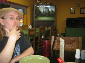 Erik, sucking on his finger in front of the big screen TV at Baldy's Pizzeria