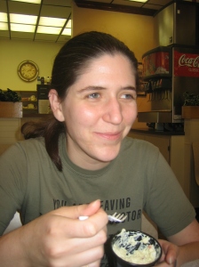 Kira, smiling around a mouthful of potato salad at the Bloomington Sandwich Co.