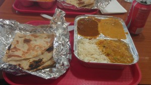 Left: naan. Upper left tray: goat curry. Upper right tray: coconut chicken. Lower left tray: daal.
